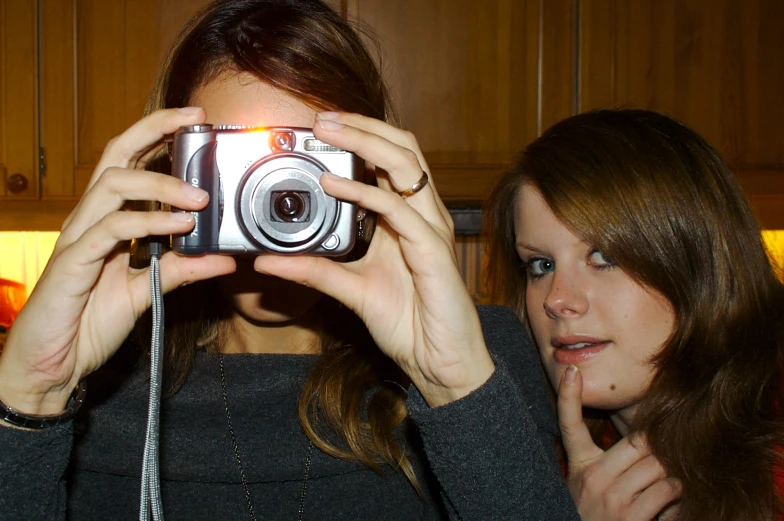 two women taking pictures with their camera in the kitchen