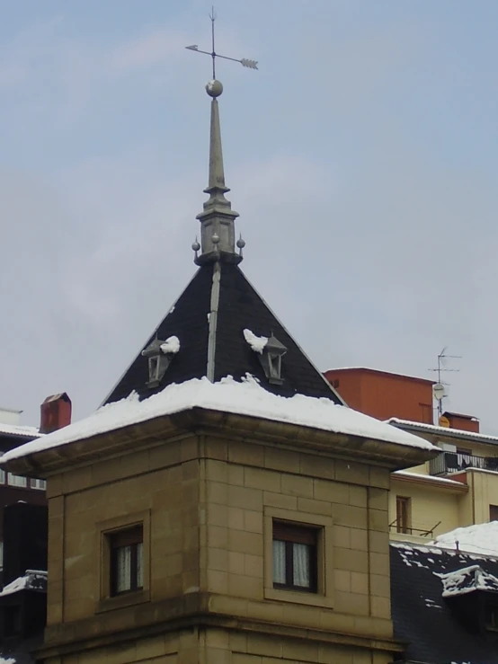 some buildings a clock and snow on the roof