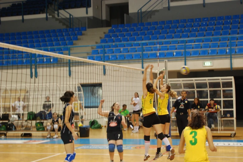 some girls are playing volleyball and some are standing in a court