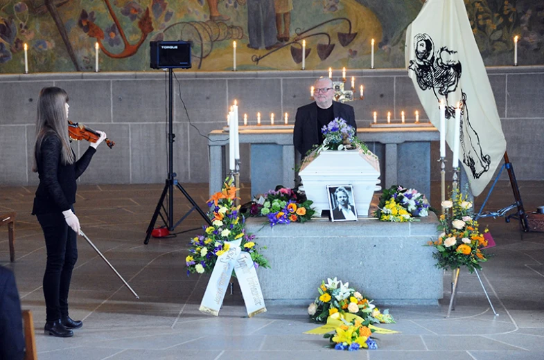 a woman with a violin standing next to a memorial