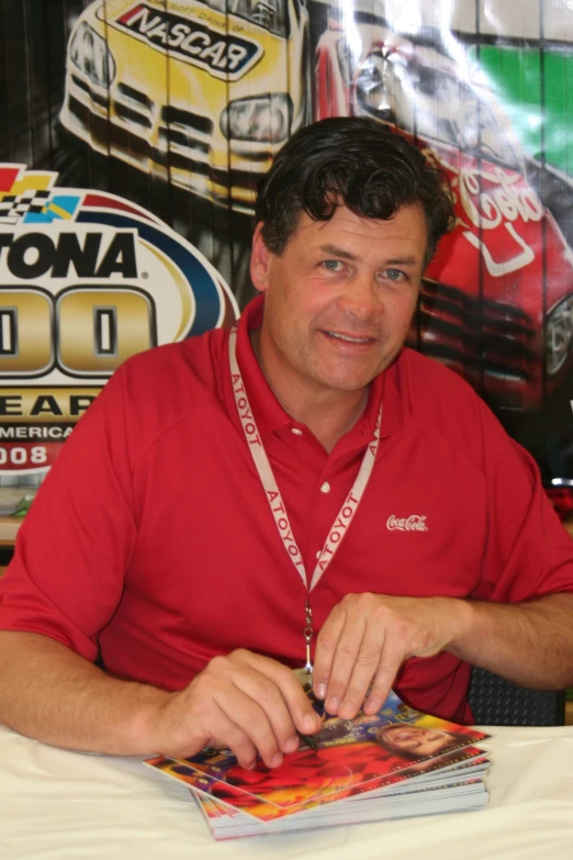 a man sitting down at a table with nascar memorabilia