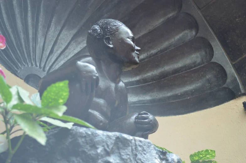 statue with flowers behind it near a large stone object