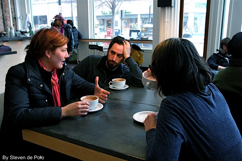 three people are eating coffee at the counter