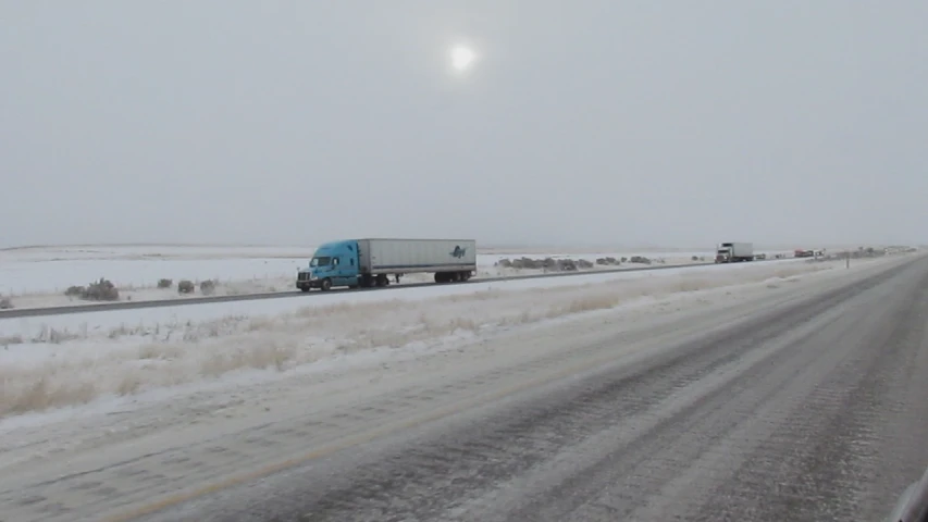 a semi driving on the road near a snow covered field