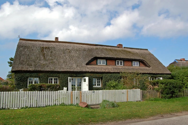 the thatch roof house has two white pickets near it