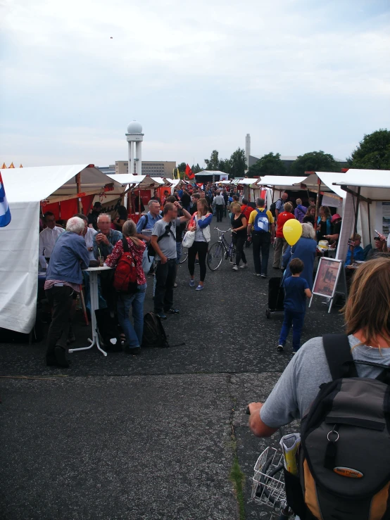 a group of people stand near tables and booths