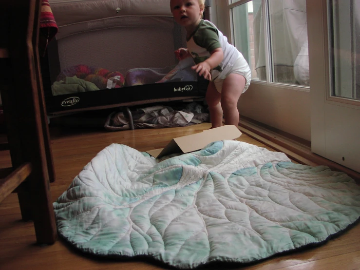 a small toddler jumping on top of a box in front of a bed