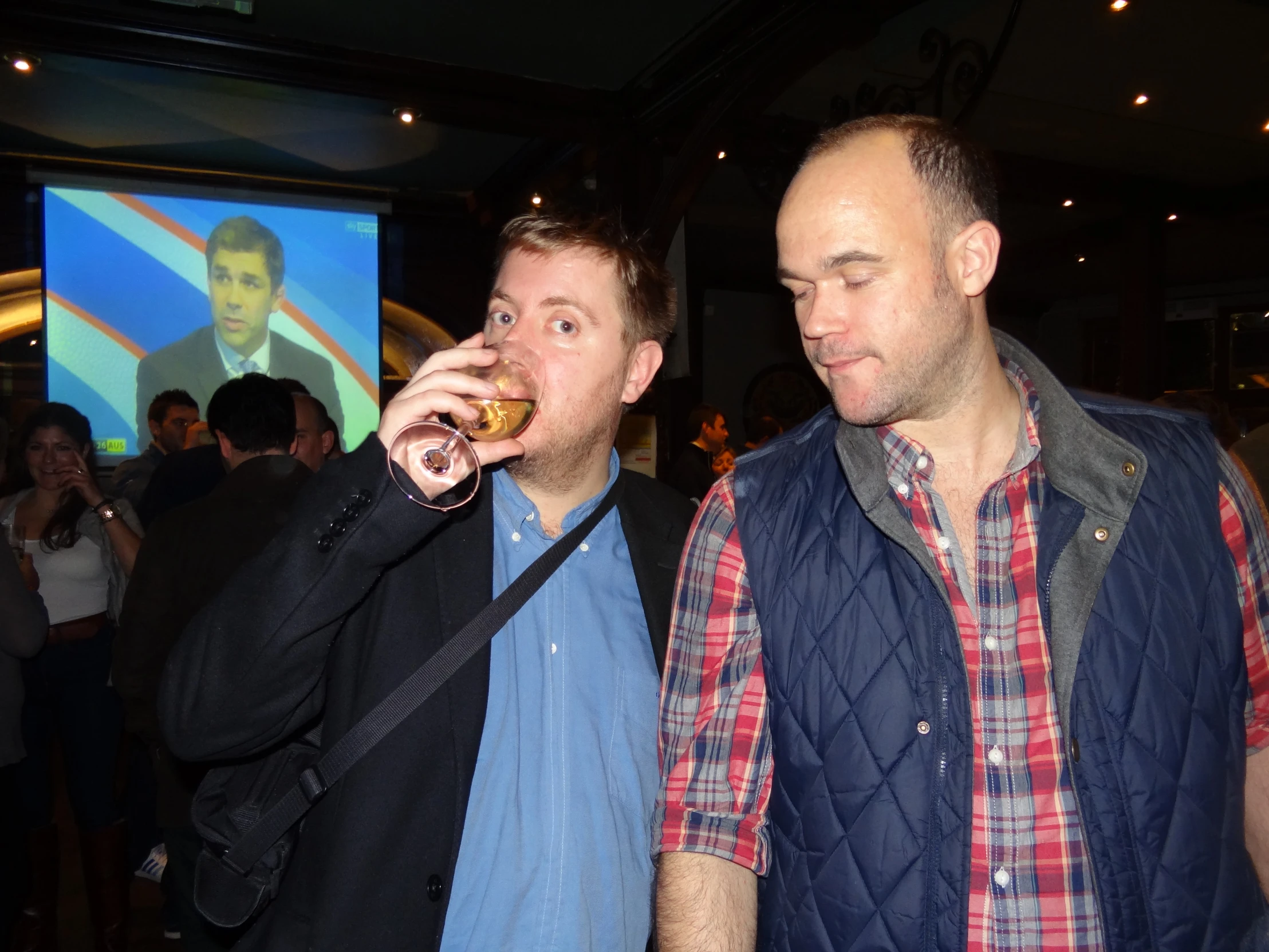 two men in a bar, one is holding a wine glass