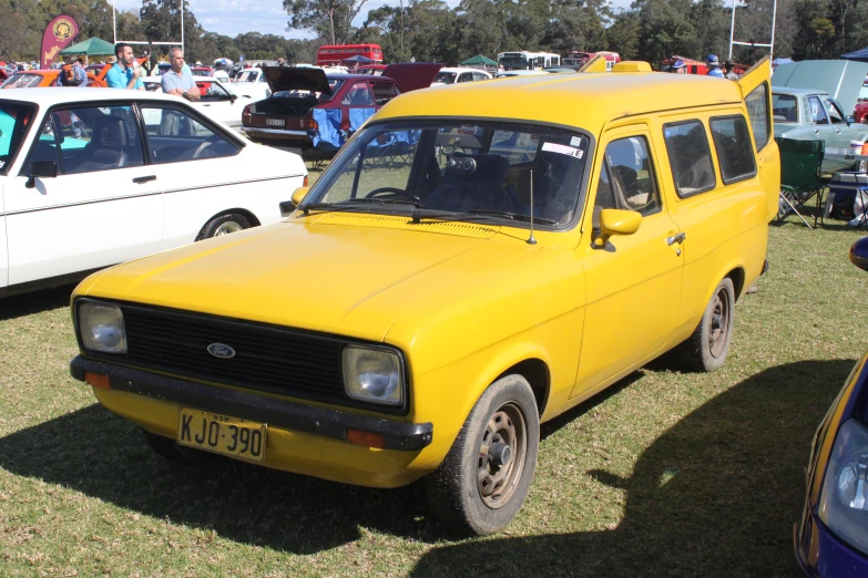an old yellow van is parked in a grassy area