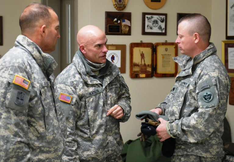 three army men in uniform are standing in a room