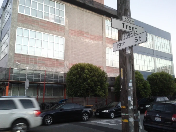 some cars driving down a street with buildings behind