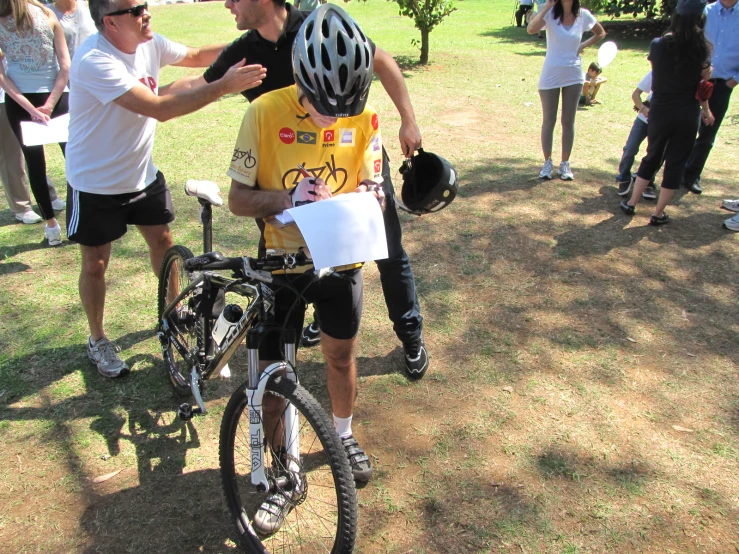 two people in helmets hold hands over a  on a bicycle