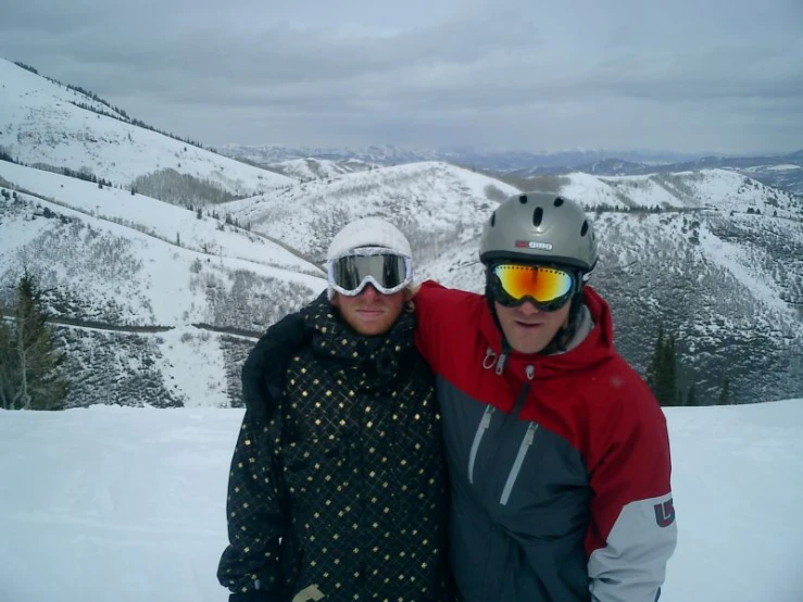 two people with skis on standing next to each other in the snow