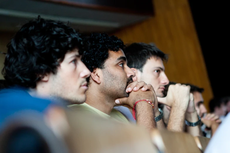 three men are sitting with their hands behind them