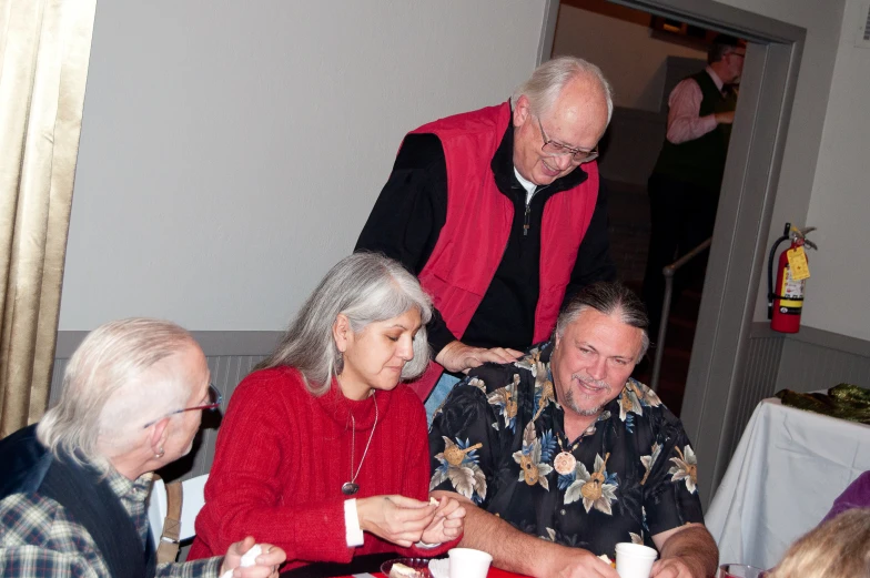 an older couple is standing next to a group of people sitting at a table