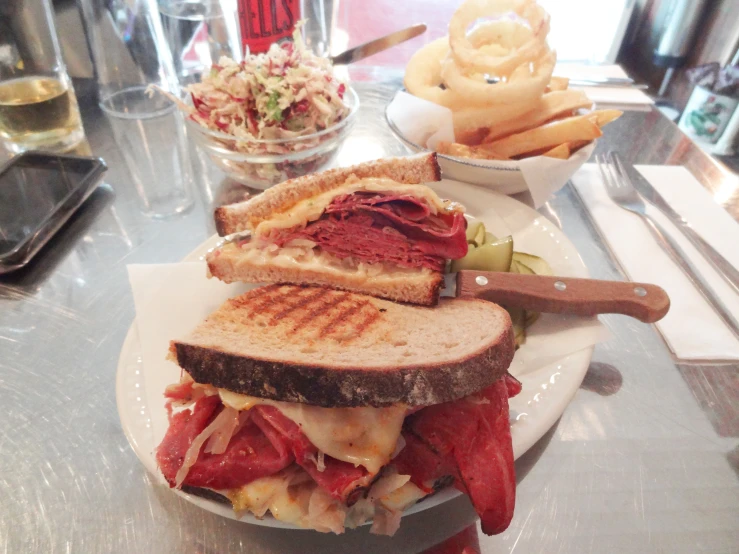 a sandwich with meat, lettuce and cheese is on a plate next to potato wedges