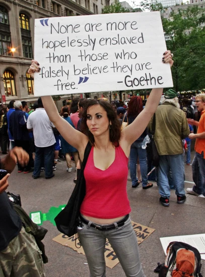 a woman holding a sign in a crowd with other people around