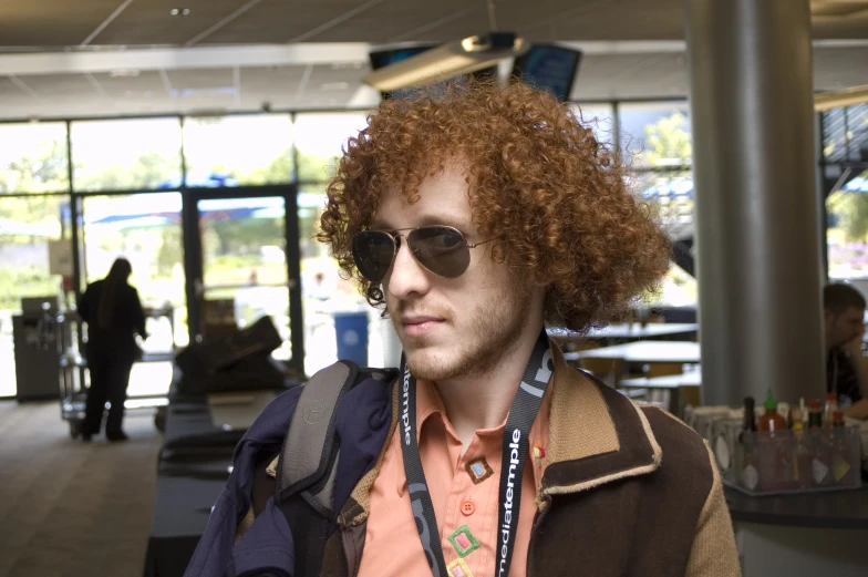 a man with red hair and sunglasses looks at the camera