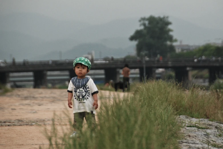 a small boy is standing in the middle of grass