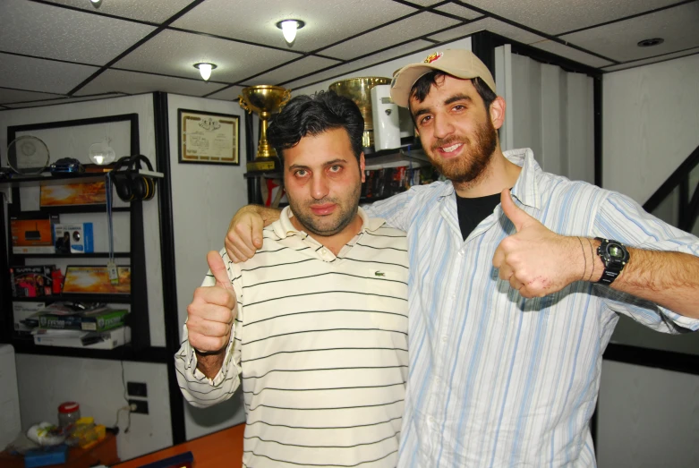 two men giving thumbs up in an office