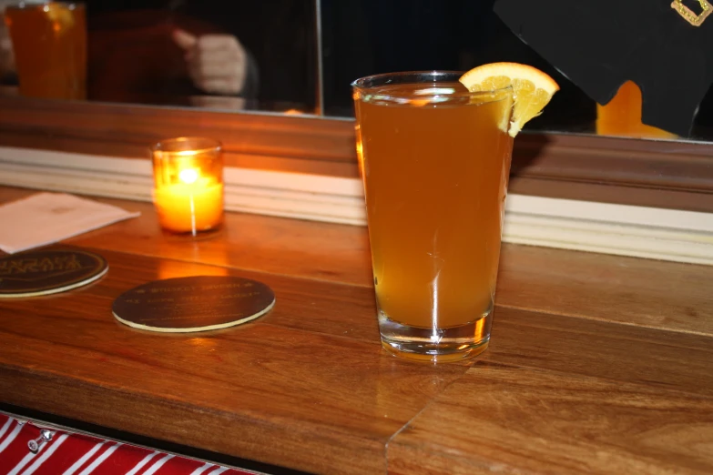 an orange slice rests in front of the drinks on a table