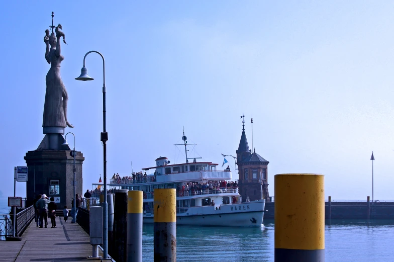 large ferry boat on pier near statue in city