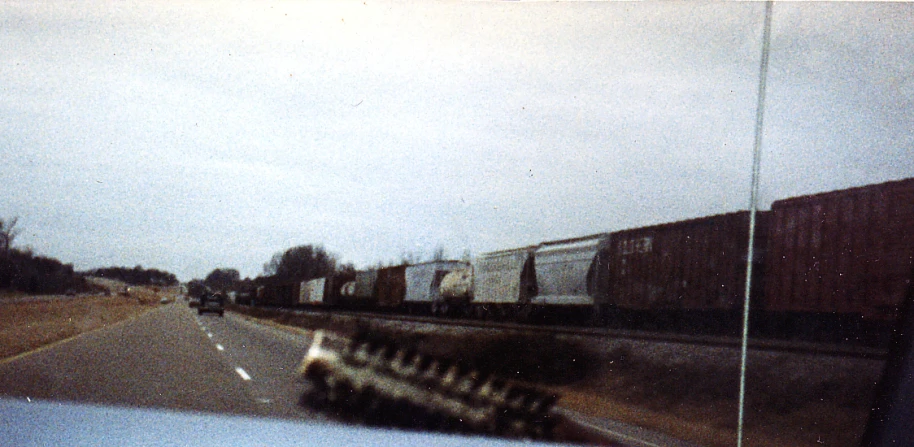a truck traveling down a road with a train on the tracks