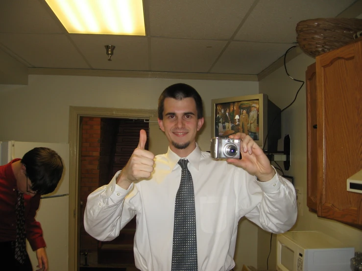 a man in a tie giving the thumbs up