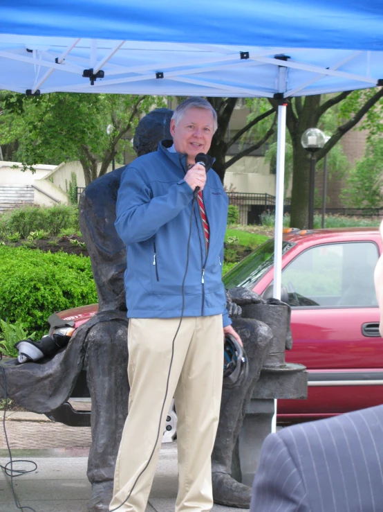 man holding microphone up standing under a blue canopy