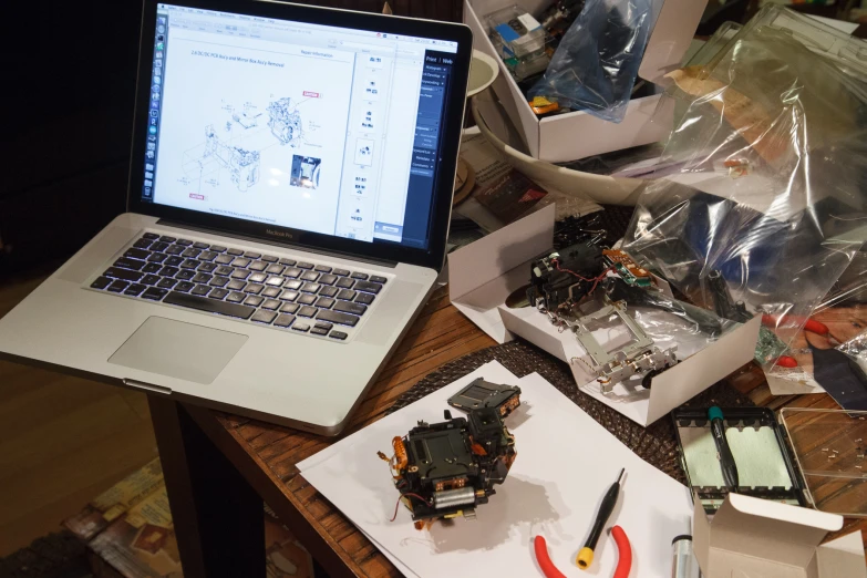 an opened laptop sits on a table surrounded by electronic equipment
