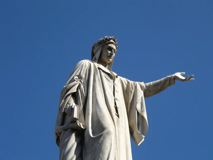 a statue holding his arm out in front of the sky