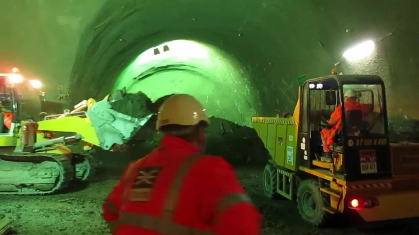 workers are standing in a tunnel next to excavating machinery