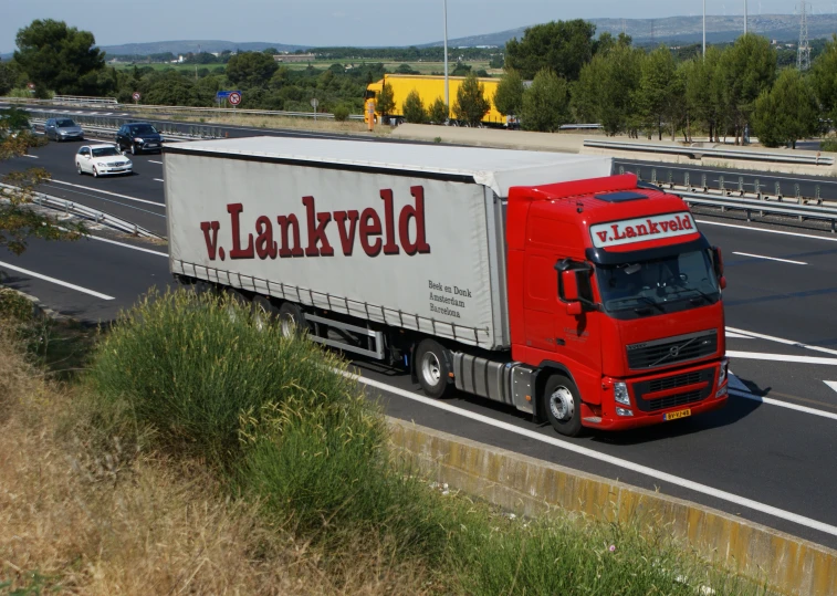 a semi truck on a road with mountains in the background