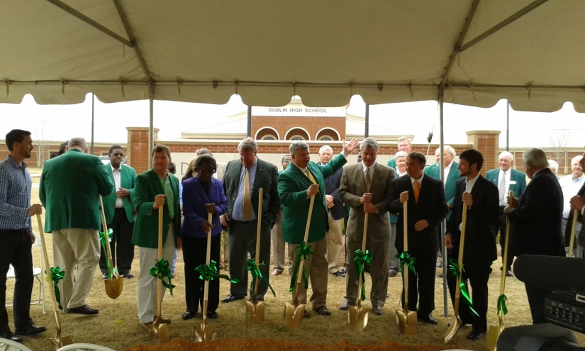 several people in front of a group of umbrellas holding shovels