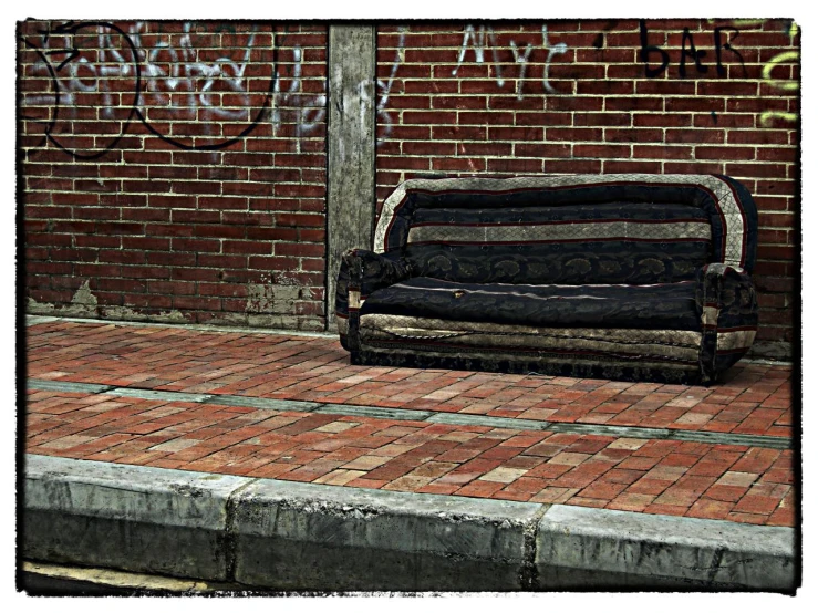 a bench on the sidewalk with graffiti writing behind it