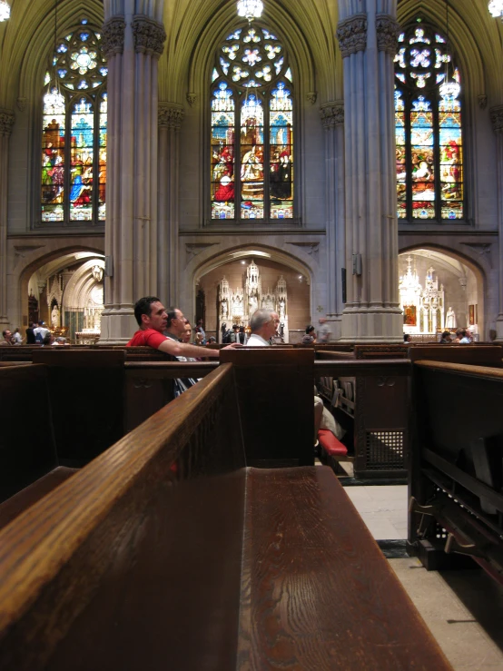 two men sit inside a cathedral in front of stained glass windows