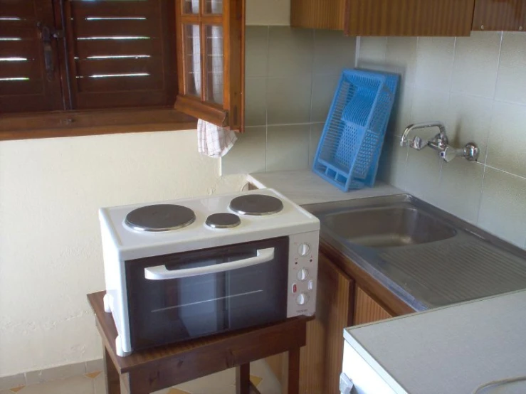 an oven and sink in a kitchen with wooden cabinets