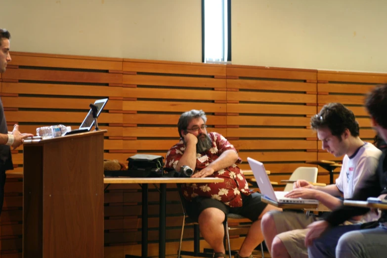 there is a man speaking into a microphone while using a laptop