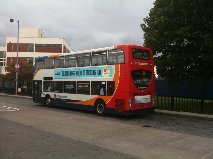 double decked city bus driving down the road near some buildings