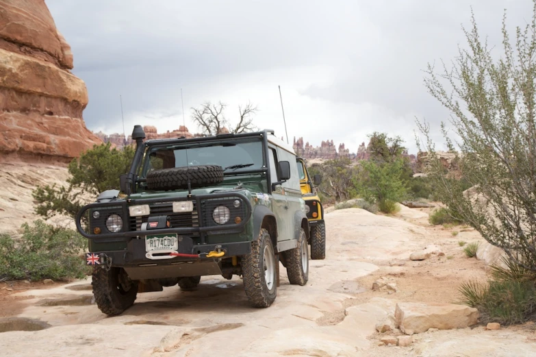 an off - road vehicle on the dirt driving near a tree and rocks