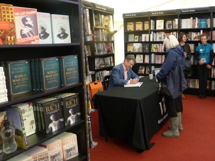 people stand in a liry talking and looking at books