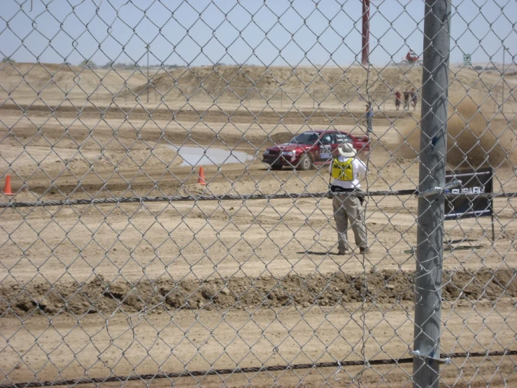a man is walking on dirt near a fence