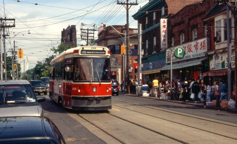 a trolley car traveling down a street near a crowd of people