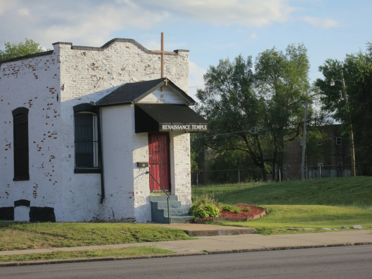 a white building with red door and grass in front