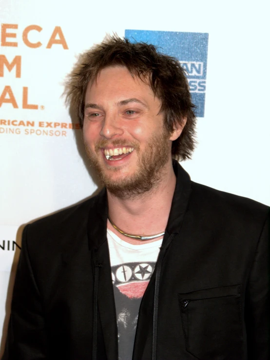 a young man with dark hair and a goatee smiling at an event