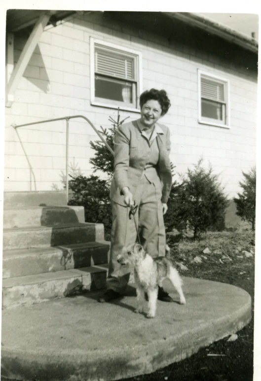 black and white po of woman outside house with small dog