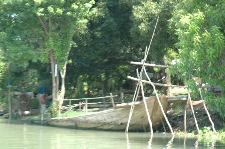 the boat is parked on the shore with trees around it