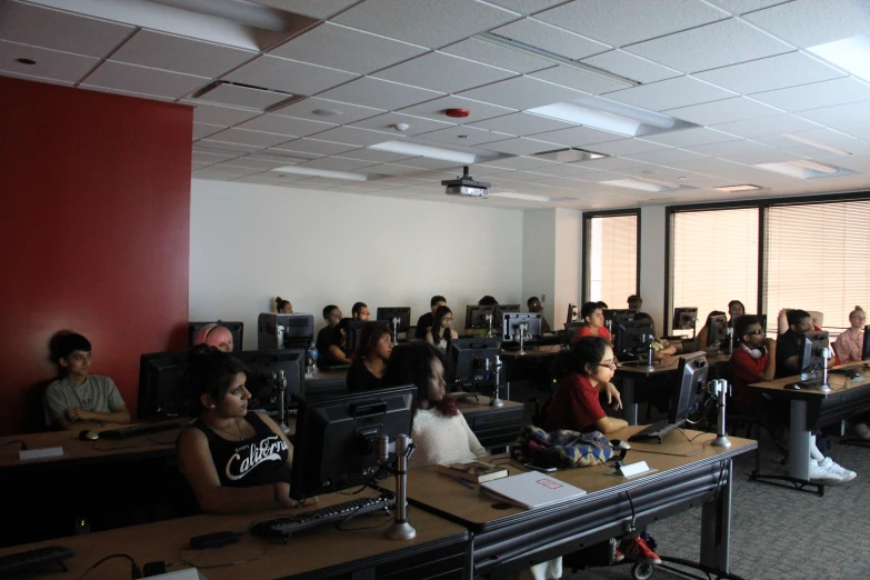 there are students sitting in a classroom using their computers