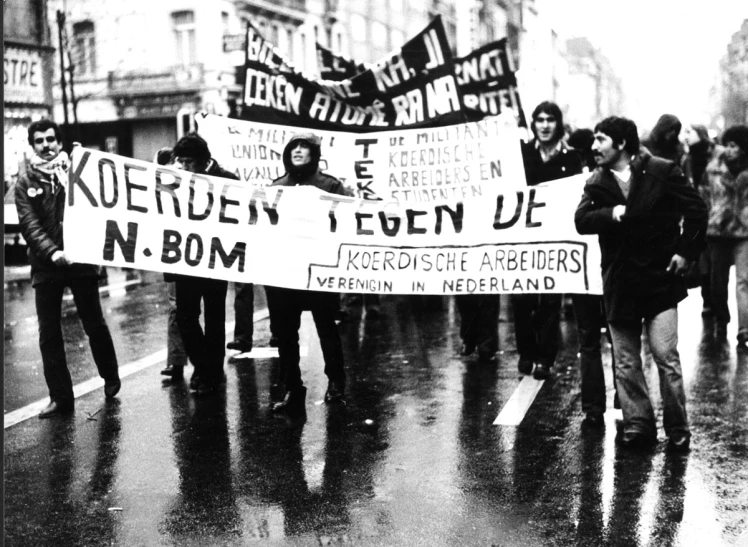 several people holding protest signs while standing on a wet street