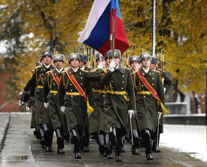 some men dressed in uniform marching with a flag